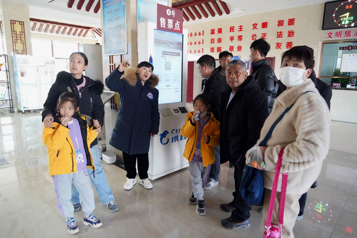 景区工作人员为游客介绍春节期间的旅游产品套餐。