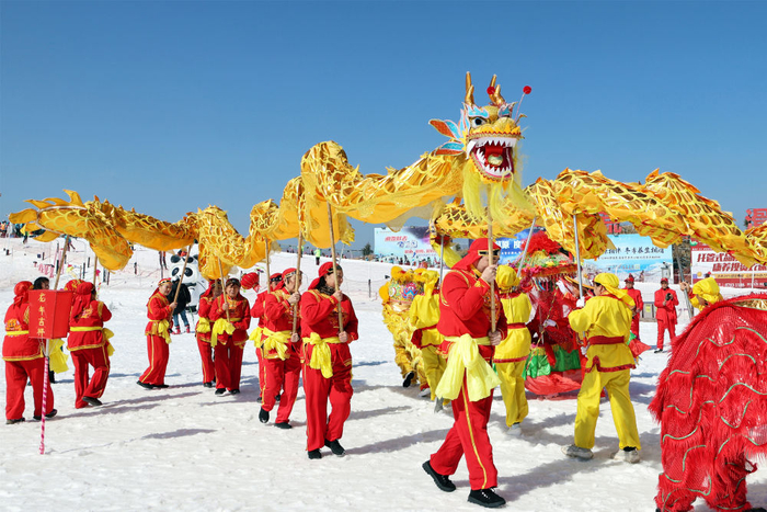 2月12日，湖北省宜昌市夷陵区民间艺术团演员在百里荒旅游度假区的滑雪场里为游客表演舞龙。新华社发（张国荣摄）