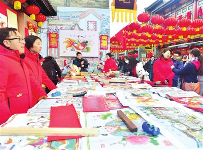 古文化街天津杨柳青画社的年画摊位吸引游客欣赏、选购。