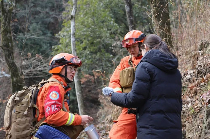 祁双红（左一）向记者介绍森林消防员背包里的物资