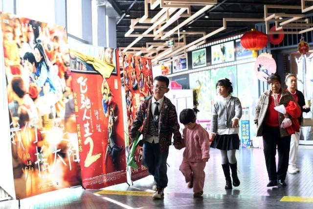 2024年2月12日，在贵州省仁怀市烽禾影城，市民从春节档电影宣传海报前经过。新华社发（陈勇 摄）