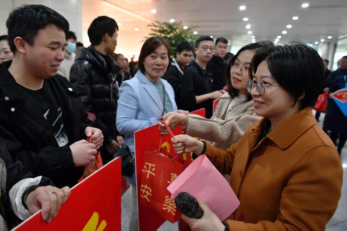 2024年2月15日,福州市人社部门工作人员(前右)向乘坐包机抵榕的返岗务工人员送上新春大礼包。当日,来自云南、贵州的364名返岗务工人员乘坐的飞机降落在福州长乐国际机场。这是2024年春节后福州市人社部门通过免费包机接回的首批重点企业返岗务工人员。新华社记者 魏培全 摄