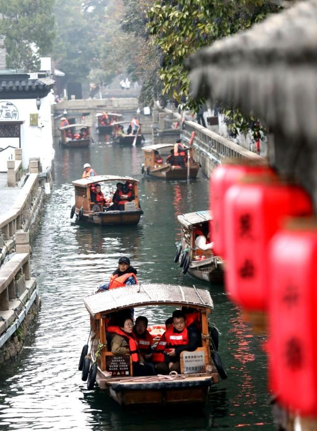 2024年2月15日，游客乘坐手摇木船游览江苏苏州平江路水巷。新华社发（杭兴微 摄）