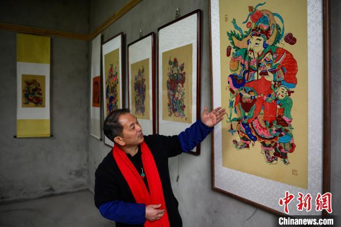 图为工作室内，徐家辉在介绍他制作的年画。中新网记者 何蓬磊 摄