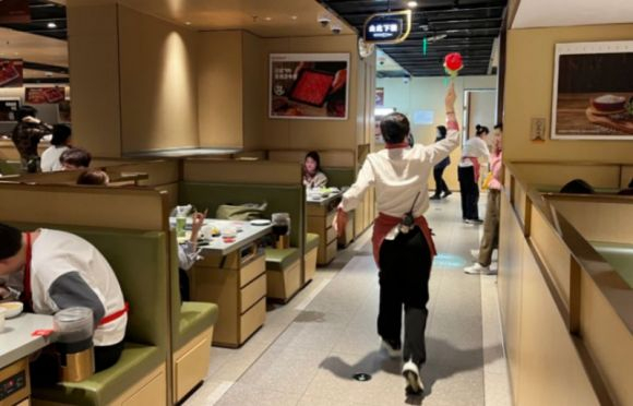 （大年初五海底捞一门店员工手执玫瑰迎接顾客）