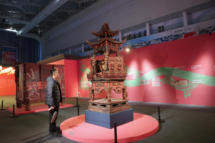 图为游客观赏刻有龙形象的木雕《杨泗将军与将军大轿》.