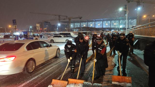 北京丰台站地区，工作人员正在清扫停车场内的积雪。北京市重点站区管委会供图