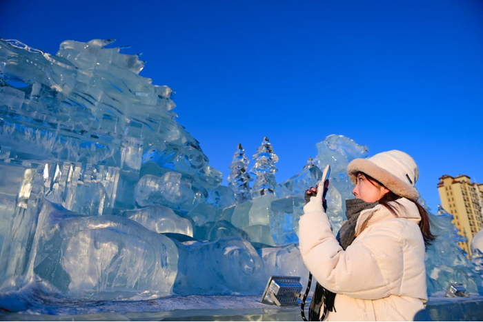 ↑2月14日，一位游客在呼伦贝尔历史博物馆广场观赏冰雕。 王正 摄