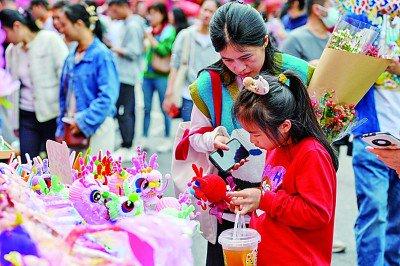 2024深圳迎春花市上，市民在挑选针织“醒龙”玩偶。 新华社发