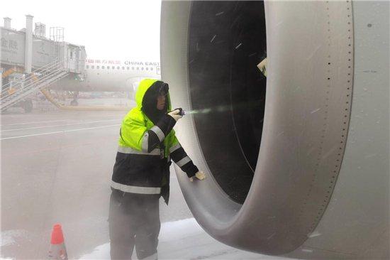 东航机务冒着大雪检查飞机发动机