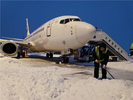东航员工清理飞机前的积雪，确保飞机能够准时准点推出