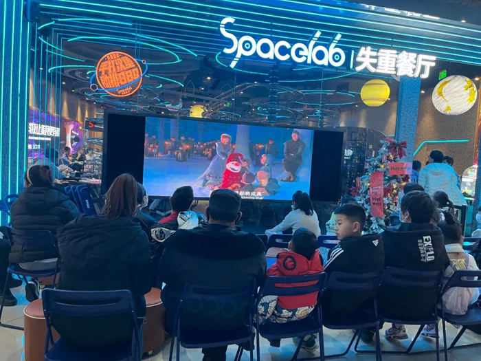  合生汇五楼一家餐厅，家长和小朋们们排队看电影。