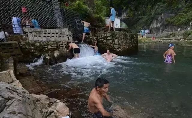 图：寻求“养生”者在广西巴马百魔洞出水口浸泡身体