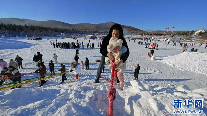 呼伦贝尔市鄂伦春冰雪“伊萨仁”活动现场，家长和小朋友进行雪地攀岩。新华网发（李霞 摄)