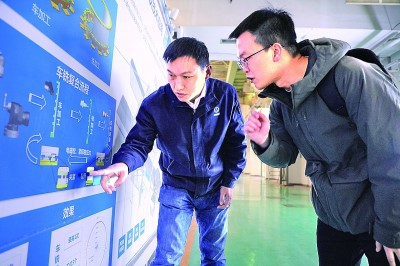 刘争向光明日报记者张晓华（右）讲述电磁装夹的工作原理。谢博宇摄/光明图片