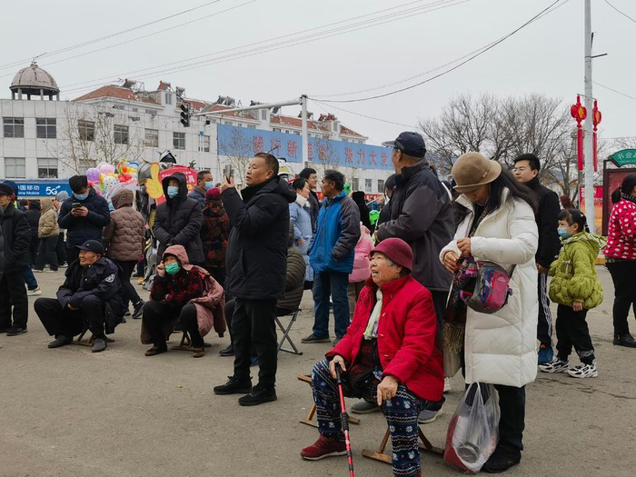 图为：陈女士坐在小马扎上，乐呵呵地看山东快书