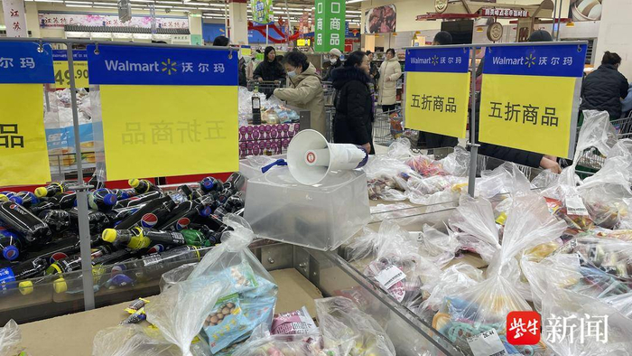 图为沃尔玛新街口店里，顾客在抢购关店前的打折商品