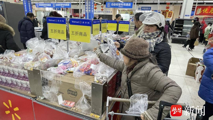 图为沃尔玛新街口店里，顾客在抢购关店前的打折商品