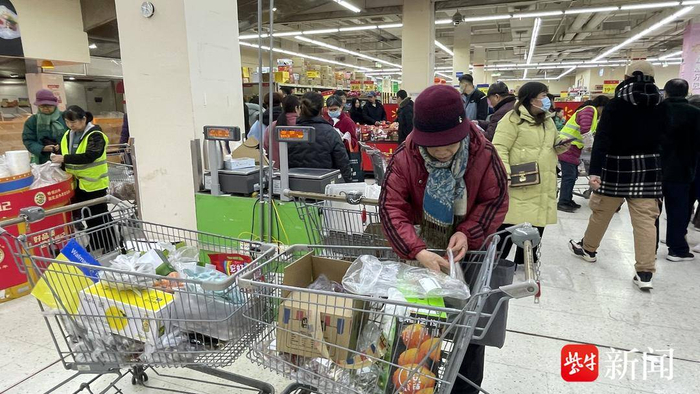 图为沃尔玛新街口店里，顾客在抢购关店前的打折商品