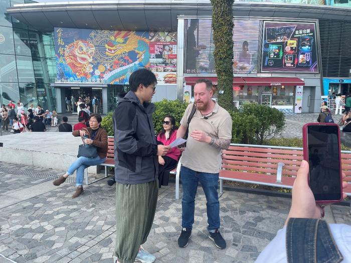 营员在香港太平山顶采访外国游客，挑战社交媒体短视频制作。