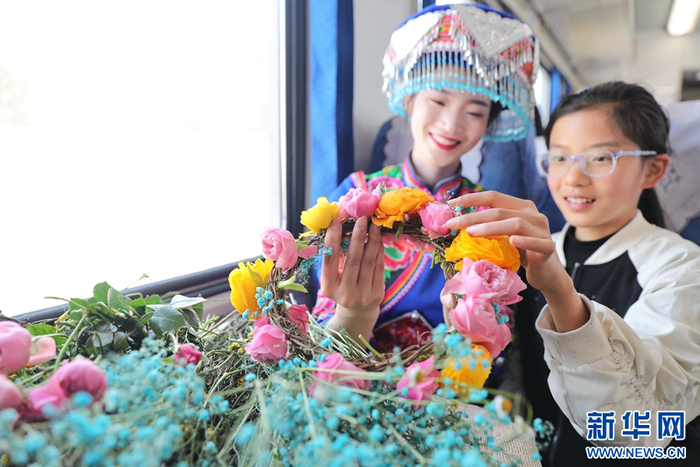乘务员和小乘客一起编制手工花环（摄于2月22日）。新华网发（杨紫轩 摄）