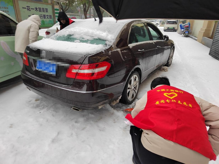 工商银行黄冈分行青年志愿者帮助路边受困车辆清理车轮下积雪（工商银行黄冈分行供图）