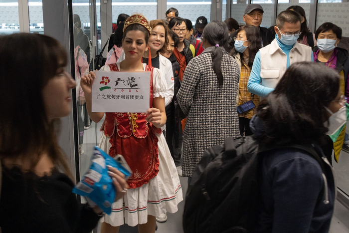 3月26日，在匈牙利布达佩斯机场，一名女士身穿匈牙利民族服装欢迎中国游客到来 图片来源：新华社