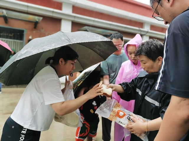 2023年8月，孟二梅（右一）冒雨为旅客发放物资。受访者供图
