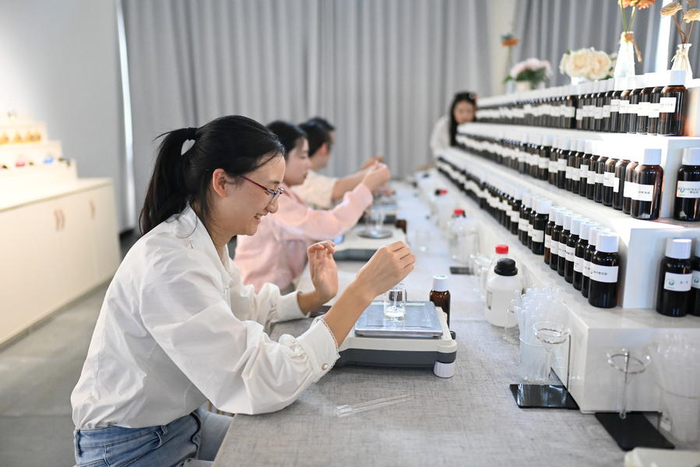 游客在江西省抚州市金溪县香谷小镇香水微生产工坊，体验香水调制乐趣。（图片由CNSPHOTO提供）