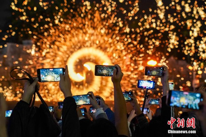   资料图：广西南宁，民众举起手机拍摄打铁花。中新社记者 陈冠言 摄