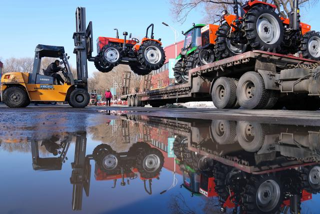 3月12日，在佳木斯骥驰拖拉机制造有限公司大院，工作人员用叉车向运输车上搬运拖拉机。新华社记者 王建威 摄