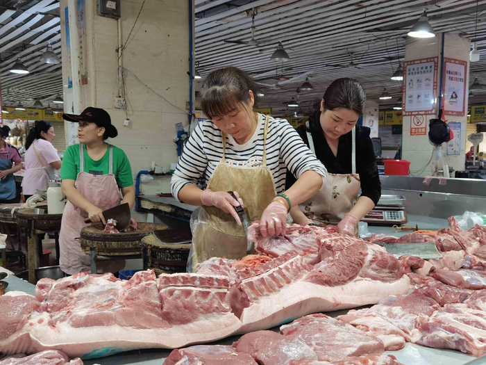 摊主正对猪肉进行切割。记者 蒙健 摄