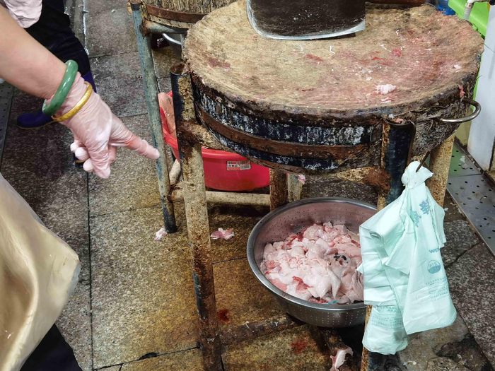 猪肉摊主将残留的槽头肉切除后丢弃处理。记者 蒙健 摄