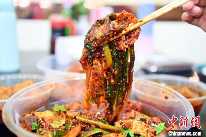 　　3月14日，甘肃省天水市秦州区，食客展示裹满红油辣子的麻辣烫。九美旦增 摄