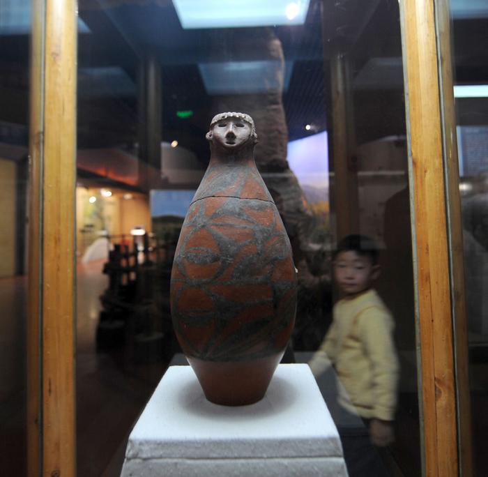 2009年10月5日，一名小朋友在甘肃省博物馆参观出土于大地湾遗址的人头形器口彩陶瓶。新华社记者 韩传号 摄