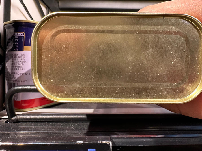 一款午餐肉罐头，经反复调整角度后，记者才隐约看到罐底印有生产日期。