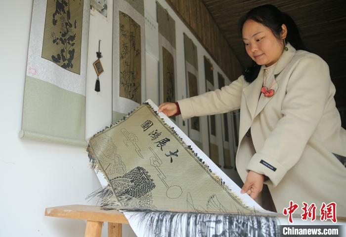 图为袁朝秀展示她正在编织的平面作品“大展鸿图”。黄兴鸿 摄