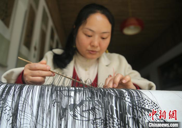 图为袁朝秀穿梭经纬，编织平面作品。黄兴鸿 摄