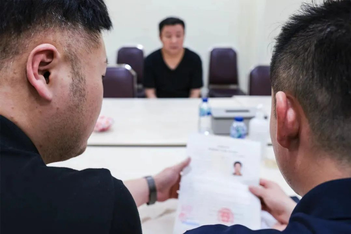 3月13日15时28分，印尼雅加达北区移民局会见室，工作组民警查看嫌疑人孙大龙相关移交资料。