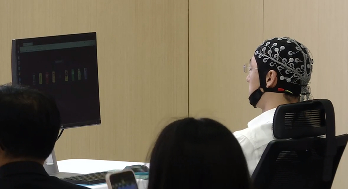 ▲工作人员在现场通过外接式脑机接口“意念”操作机器人