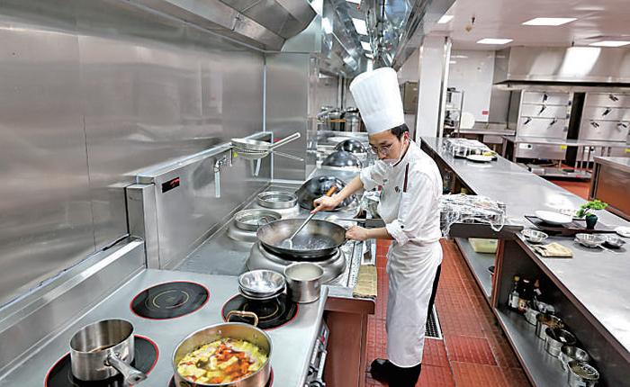 厨师在博鳌亚洲论坛大酒店厨房里使用电气化改造后的电气炉灶炒菜。新华社发