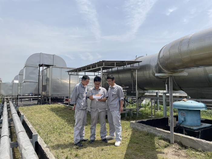 图为维修人员探讨环保新工艺。楼子微 摄