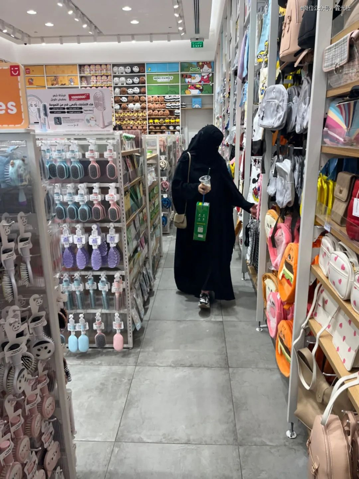 在利雅得商场内MINISO购物的沙特女性，手捧一杯中式奶茶。