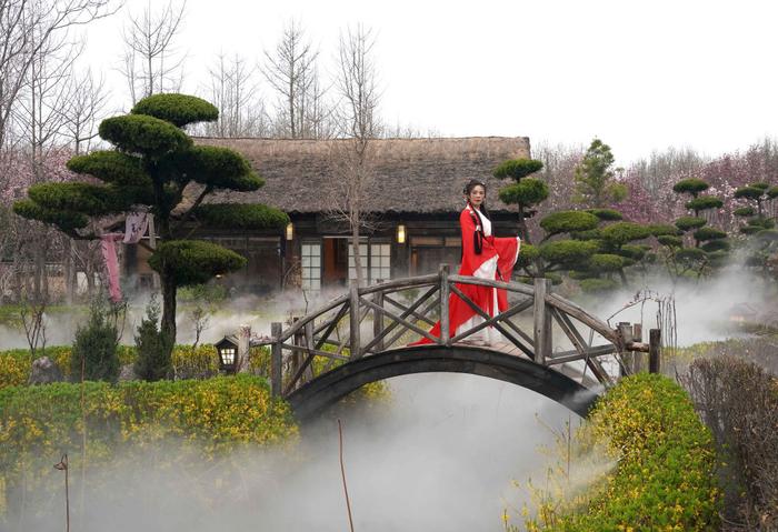 身着传统服饰的游客在位于河南省鄢陵县的一处园林内拍照（3月26日摄）。新华社记者 李安 摄