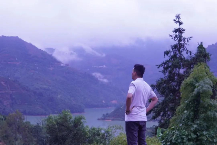 ▲魏宏羽站在家门口，远处就是水库。