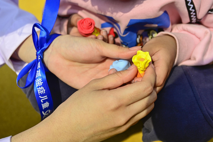 ▲4月2日，山东青州志愿者为孤独症患者献上彩泥制作的花朵 据视觉中国