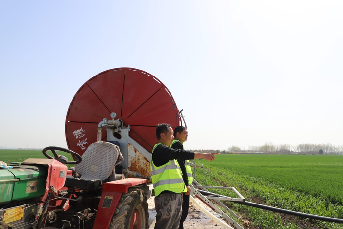 村民谭龙飞正在和邻里一起查看小麦灌溉情况。胡少佳摄