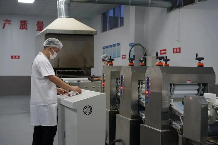 李震震在操作小饼生产线。陈淑莲/摄