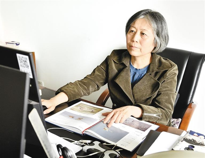 刘秋莲对照鸟类图册整理自己拍摄的照片  记者 杨力 摄