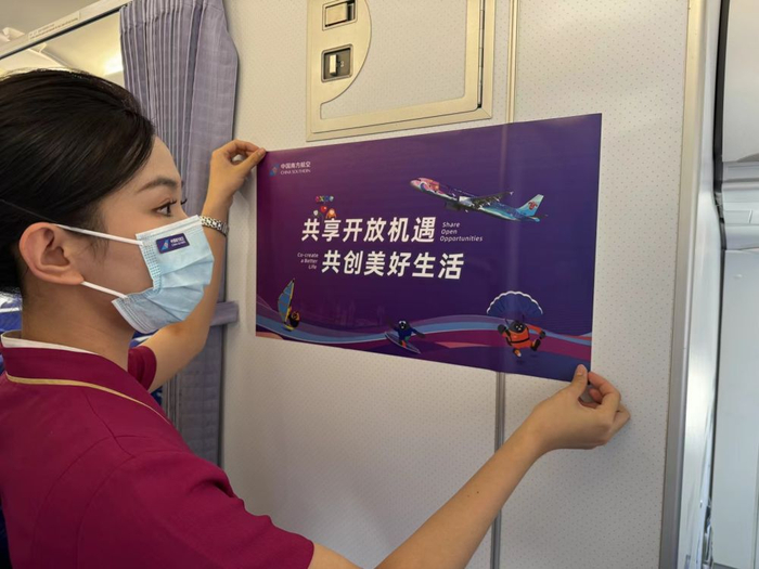 ↑4月12日，南航乘务员正在用消博会主题贴纸装饰客舱。高晗 摄